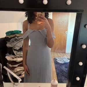 Ljusblå axelbandslös klänning - Säljer en elegant ljusblå axelbandslös klänning med volangdetaljer vid bysten. Perfekt för sommarens festligheter. Klänningen har en smickrande passform och är i ett mjukt material. Funkar till bröllop och bal!