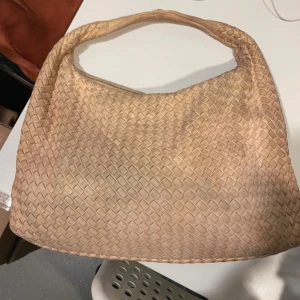 Bottega Veneta  - Påsen har inte försökt rengöras eller liknande. innan, därför kan vissa fläckar lossna. Man kan se att väskan är använd, men den har fortfarande många bra år kvar i sig. Färgen är lite babyrosa/persika, men lite missfärgad.Finns en liten spegel med väskan. 