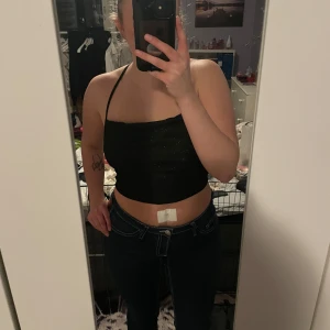 Svart korsettopp - Snygg svart topp med korsade band i ryggen. Perfekt för en stilren och modern look. Den är glittrig så passar perfekt till fest eller nyår. Den är aldrig använd så är i bra skick💞