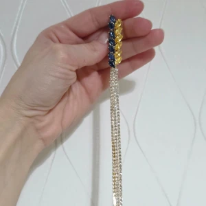 Långa brocho öra med blå och gula stenar - Elegantabrocho öra långa örhängen med blå och gula stenar i en bladformad design. De har flera rader av glittrande stenar som hänger ner och ger en lyxig känsla. Perfekt för att lägga till en färgklick till din outfit.