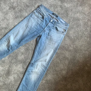 Blå jeans från Replay - Snygga ljusblå jeans från Replay med straight fit. Klassisk femficksdesign och knappgylf. Perfekta för en avslappnad stil. Märkesdetaljer på fickan och bältesslingor för extra stilpoäng.