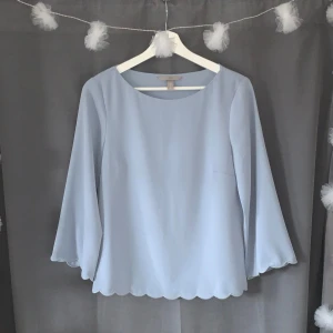 Ljusblå blus från H&M - Elegant ljusblå blus från H&M med vågig kant. Blusen har en rund halsringning och är använd fåtal gånger 🩵