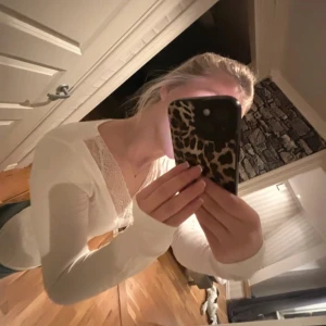 Vit långärmad topp från Gina Tricot - Säljer en stilren vit långärmad topp från Gina Tricot med v-ringning och spetsdetaljer. Perfekt för en elegant look. Passar bra till jeans eller kjol.