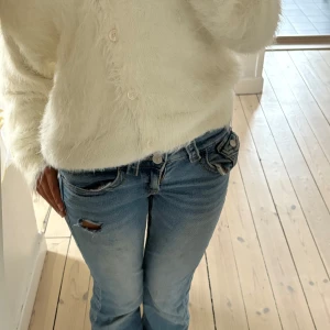 Ljusblå bootcut jeans med slitning - Säljer ett par ljusblå jeans med en snygg slitning som jag gjort själv 💘 jeansen är bootcut och low waist. Säljer då de tyvärr inte kommer till användning längre 💓 