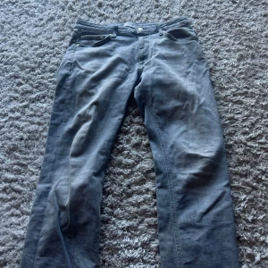 Grå jeans från Jack & Jones, strl 32 - Snygga grå jeans från Jack & Jones i modellen Clark. Klassisk femficksdesign, raka ben och normal passform. Jeansen är tillverkade i mjukt bomullsmaterial och har en stilren look som passar till det mesta.