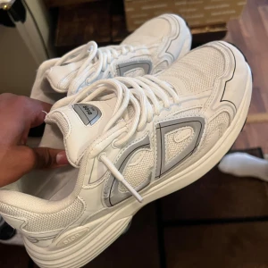Dior B30 43/44 - Snygga vita Dior sneakers med stora CD-detaljer på sidan och silvriga inslag. Tveka inte på att höra av er vid frågor eller andra bekymmer 🙌