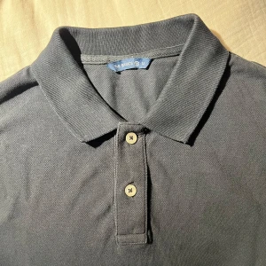 Svart pikétröja  - Svart pikétröja i storlek M. Klassisk krage och två knappar framtill. T-shirten är gjord i bomull och har korta ärmar. Perfekt för en clean och enkel look, funkar till jeans eller shorts. Skriv om du har frågor🙌