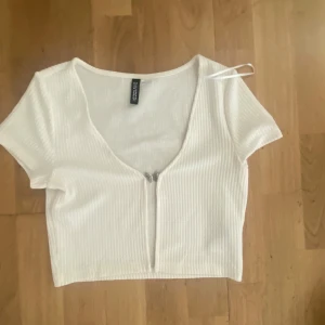 Vit croppad ribbad topp från Divided - Säljer en vit croppad topp från Divided med korta ärmar och v-ringning. Aldrig använd🥰