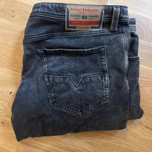 Svarta jeans från Diesel W36 - Säljer ett par svarta jeans från Diesel i klassisk tvätt. Jeansen har raka ben, femficksmodell och snygga detaljer på bakfickan. Märkespatch bak i midjan och diskreta sömmar. Perfekta för dig som gillar en stilren look.