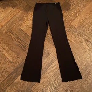 Svarta vida byxor från H&M Move - Svarta byxor från H&M Move i stretchigt material med lätt ribbad struktur. Vida ben och enkel, stilren design. Tillverkade i 95% bomull och 5% elastan för en bekväm passform. Perfekta för en chill och trendig look.