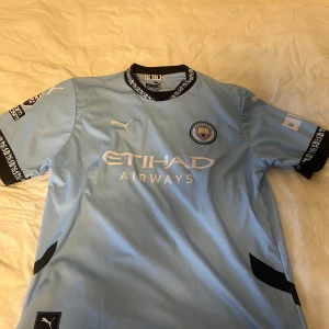 Manchester City hemmaställ 24/25 - Den perfekta tröjan för alla City-fans – oavsett om du vill bära den på matchdag, träning eller som vardagsplagg. Med Haaland #9 på ryggen representerar du en spelare som redan skrivit in sig i klubbens historia. Tröjan är i storlek M, säljer den pga för att jag håller på united och fick den som present. Bara legat i gaderoben och skräpat. Inga defekter alls. Priset kan diskuteras vid snabb affär vill bara få den såld.