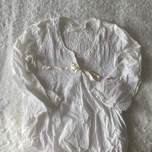 Vit blus från Odd Molly - Super söt vit blus från Odd Molly. Den har ett mönstrat tyg med trekvarts ärmar. Toppen har en rosett längst fram och en liten rosa rosett på armen. Perfekt att matcha med ett par jeans eller en kjol. Hittar tyvärr inte storlek men skulle säga att den sitter som en M. 