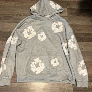 Grå hoodie, Denim Tears - Snygg grå hoodie från Denim Tears. Klassisk känguruficka framtill och huva. Perfekt för dig som gillar streetwear och vill sticka ut med en unik design. Aldrig använd pågrund av storleken på den.