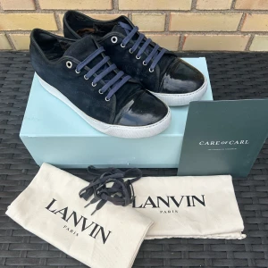 Lanvin  - Säljer ett par marinblå Lanvin sneakers med snygg kombination av mocka och lackad tå. Använt skick men har mycket att ge, lite smutsiga, sliten sula och häl, (se bilderna) om du har frågor är det bara att fråga eller om du vill ha fler bilder, uk 10 som är 44 ish, obs sulkräm har använts. Box och allt og medföljer inte!