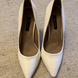 Vita pumps med spetsig tå - Stilrena vita pumps från Vices i lack material med spetsig tå och smal hög klack. Klassisk och elegant modell som lyfter vilken outfit som helst. Perfekta för dig som gillar en clean och chic look.