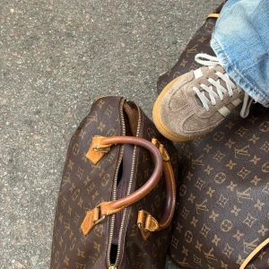 Louis Vuitton Keepall Monogram väska - Säljer en klassisk Louis Vuitton Keepall med ikoniskt monogrammönster i brunt och beige. Väskan har robusta handtag i skinn, mässingsfärgade metalldetaljer och dragkedja. Perfekt storlek för weekendresor och riktigt snygg att bära till allt.