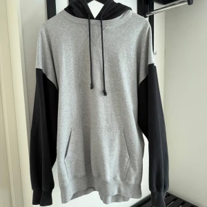 Grå och svart hoodie från Brandy Melville - Säljer en hoodie från Brandy Melville i grått med svarta ärmar och huva. Tröjan har känguruficka framtill, dragsko i huvan och är långärmad. 