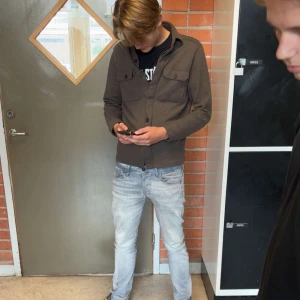 Mörkbrun kofta med knappar - Säljer en mörkbrun kofta med knappar framtill och två bröstfickor med lock. Koftan har en klassisk krage och är långärmad, perfekt för lager-på-lager. Passar dig som gillar en clean och enkel stil. BYTE FUNKAR!