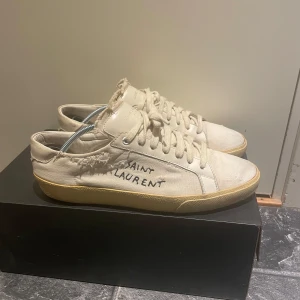 Saint Laurent vita sneakers med råa kanter - Säljer ett par Saint Laurent Paris sneakers, modell Court Classic SL/06 “Distressed”Färg: Off-white/beige med gulnad retro-sula slitningen är en del av designen! Nypris 5000kr   