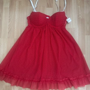 Ny. Röd prickig nattlinne med rosett - Supersöt röd nattlinne med vita prickar och tunna axelband. Linne har vadderade kupor, liten vit rosett framtill och volangkant längst ner. Svalt och lätt material, perfekt för varma dagar. Ordpris 199 kr,nu 100kr, storlek 38, men den är förminskad och mer som 34/36