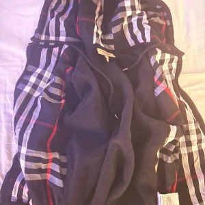 Rutig hoodiejacka från Burberry - Snygg hoodiejacka från Burberry med klassiskt rutigt mönster i svart, vitt och rött. Jackan har dragkedja, snörning i huvan och är tillverkad i mjuk bomull. Perfekt för dig som vill ha en ikonisk streetstyle-look med premiumkänsla.