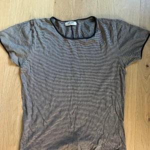 Randig t-shirt från Acne Jeans - Säljer en tunn, randig t-shirt från Acne Jeans i svart och vit. T-shirten har rund halsringning med svarta kanter och korta ärmar. Perfekt för en clean och avslappnad stil. Rätt liten i storleken så någonstans mellan xs-s. Psssar både killar och tjejer, hel och ren. Finns på Söder i Stockholm 