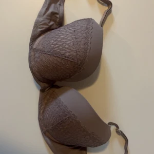 Beige spets-bh 75B - Säljer en beige bh med snygga spetsdetaljer på kuporna. Bh:n har justerbara axelband och slät baksida. Perfekt för dig som gillar en stilren look med lite extra detaljer. Kuporna är lätt vadderade och ger bra stöd.