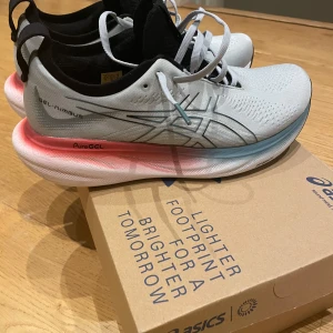ASICS Gel-Nimbus 25 grå sneakers endast använda en löprunda!  - Säljer ett par nya lyxiga löparskor ASICS Gel-Nimbus 25 i färgen Piedmont Grey/Foggy Teal. Skorna har en snygg ljusgrå ovandel med svarta och blå detaljer, samt en cool sula med rosa och blå toner. Perfekta för löpning eller träning, med PureGEL-dämpning och ventilerande meshmaterial. Använda mindre än en timma. Nyskick! 