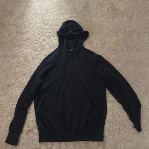 Marinblå tröja från Massimo Dutti - Svart hoodie från Massimo Dutti med huva och snörning. Tillverkad i en mjuk blandning av bomull och kashmir. Vet ej vilken storlek den är för det står inte med skulle säga XS eller S