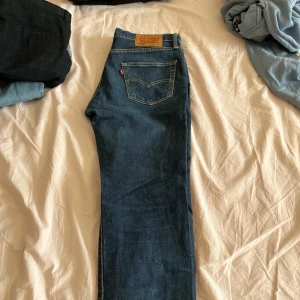 Levi's 511 blå jeans W33 L30 - Säljer ett par klassiska Levi's 511 jeans i blå denim. Modellen har normal passform med något smalare ben och snygga kontrastsömmar. Ikonisk läderpatch bak och röd Levi's-tagg på bakfickan. Perfekta till sneakers eller boots.