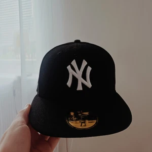 New era keps! - Säljer en svart New Era 59FIFTY keps med klassiskt NY Yankees broderi i vitt framtill. Kepsen har rak skärm och broderade loggor på sidan och bak. Tillverkad i 100% polyester och har en clean, sportig look.