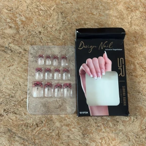 Design Nail lösnaglar med mönster - 12 st lösnaglar med transparent bas och rosa tippar dekorerade med svarta, lekfulla mönster. Naglarna är fyrkantiga. Perfekt för dig som vill ha en unik och kreativ nageldesign. ( kommer utan lim eller klister)