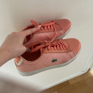 Lacoste rosa sneakers strl 38 - Snygga rosa Lacoste sneakers i modellen Carnaby Evo. Skorna har mesh- och skinnpaneler, klassisk snörning och vit sula. Ikoniska krokodilloggan på sidan och Lacoste-märke bak. 