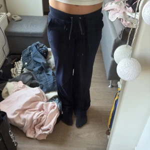 Mörkblå mjukisbyxor Juicy Couture XXS - Mörkblå mjukisbyxor från Juicy Couture med snörning i midjan och fickor med knappdetaljer bak. Sköna och klassiska byxor i mjukt material, perfekta för chill dagar. Snygg loose passform och låg midja för en avslappnad vibe. 