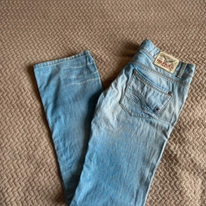 Ljusblå bootcut jeans Tommy Hilfiger - Snygga ljusblå jeans från Tommy Hilfiger med bootcut passform. Klassisk femficksdesign, Hilfiger-logga på bakfickan och patch på linningen. Jeansen är i denim med slitningar och ljusa tvättade partier för en cool look.