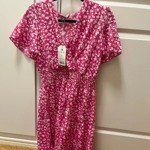 Rosa blommig klänning från Moraj - Säljer denna super söta och snygga klänningen . Perfekt till sommaren och psssar perfekt till färgerna!!💕 aldrig använd , pris lap kvar 