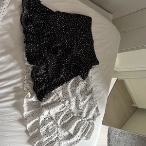 Prickiga volangkjolar i svart och vitt - Två superfina korta kjolar med volanger och prickigt mönster. En är svart med vita prickar och den andra är vit med svarta prickar. Båda har en omlott-look och volangdetaljer längs nederkanten. Perfekta för dig som gillar en trendig stil. Köpta på plick så de två sista bilderna är lånade från förra ägaren! Men kjolarna kommer från shein ursprungligen 💕💕säljer dem tillsammans för 50 kr men om man önskar att köpa en av dem får man skriva de💕