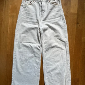 Vita wide jeans från Pull&Bear - Snygga vita jeans från Pull&Bear med hög midja och raka, vida ben. Jeansen har råa kanter nertill för en trendig look och klassiska fem fickor. Tillverkade i bomull med dragkedja och knapp framtill.