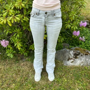 Ljusgrå bootcut jeans  - Snygga ljusgrå jeans med bootcut passform och coola fickdetaljer bak med knappar och broderade mönster. 🩷 Midja: 36cm 🩷 Ytterben: 101cm 🩷 Innerben: 79 cm 🩷