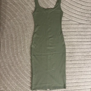 Grön midi klänning - Tight klänning från Zara med en slit på baksidan. Klänningen är i nyskick och har använts kanske ett par gånger. 