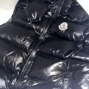 Svart dunväst från Moncler med huva - Säljer en svart, glansig dunväst från Moncler med avtagbar huva och dragkedja framtill. Västen har två fickor med dragkedja och klassisk Moncler-logga på bröstet. Perfekt för lager-på-lager och riktigt snygg till streetwear.
