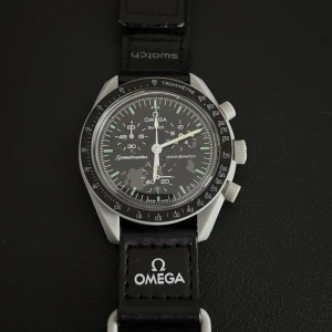 Omega x Swatch MoonSwatch - Säljer en Omega x Swatch Speedmaster MoonSwatch 'Mission to the Moon'. Klockan har svart urtavla med vita detaljer, tachymeter och flera subdials. Boetten är grå och bandet är svart med Omega och Swatch-loggor. En riktigt ikonisk och stilren klocka med cool rymd-inspiration. Pris kan diskuteras vid snabb affär
