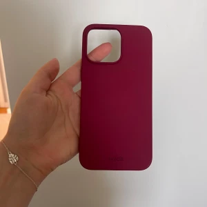 Burgundy mobilskal från Holdit - Säljer ett stilrent mobilskal från Holdit i en snygg mörkröd nyans. Skalets yta är matt och slät, och det är designat för att passa perfekt runt kameran. Perfekt för dig som vill ha ett enkelt men trendigt skydd till mobilen. Helt oanvänt, säljes pga fel storlek. För iPhone 15 PRO Max.