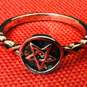 Ny ring med pentagram Stål Goth Metal Wicca Witchy - Ny ring i Stållegering med flätad detalj på sidorna och tydlig pentagram-symbol i mitten. Innerdiameter ca 20 mm. Perfekt för dig som gillar alternativ stil, goth, wicca eller ockult estetik. Passar både till vardags och som ett statement. Ny och oanvänd.  Ingen prutning, men jag erbjuder bundlerabatt. Jag rensar både smyckesskrin och garderob – kika gärna på mina andra annonser också!  