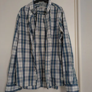 Blårutig Peak Performance skjorta S - Snygg blårutig skjorta från Peak Performance i slim fit-modell. Skjortan har klassisk krage, långa ärmar och knäppning framtill. Tillverkad i 100% bomull och har detaljerade etiketter både i nacken och vid knappslån. Perfekt för en avslappnad men stilren look.