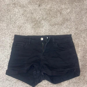 Svarta jeansshorts från H&M - Svarta jeansshorts från H&M i klassisk femficksmodell med uppvikta benslut och dragkedja framtill. Snygg midwaist-passform som är enkel att matcha med allt. Perfekta för varma dagar och chill outfits. Pris kan diskuteras❤️ 