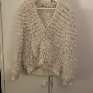 As mysig vit fluffig kofta  - Säljer en unik vit kofta från Cosmo med fluffig textur och knappar framtill. Den har en v-ringad design och långa ärmar, perfekt för att hålla sig varm och stilren. Passar bra till både jeans och kjol. Perfekt för kyliga dagar! Passar XS-L beroende på hur man vill att den sitter 💓💓💓💓💓