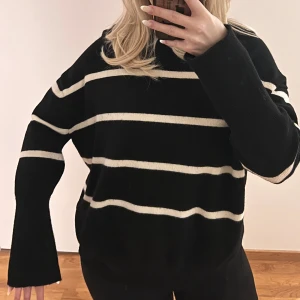 Stickad tröja från Bikbok  - Säljer en svart stickad tröja med vita ränder från bikbok i storlek XS. Tröjan har långa ärmar och en avslappnad passform. Den har även en liten slits vid sidorna på tröja. Väldigt bra skick. Köparen står för frakten. 
