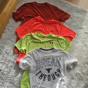 4st Under Armour T-Shirts - Säljer 4st snygga T-Shirts från Under Armour. En från Projekt Rock med texten 'BREAK THROUGH' och en liten tjur-logga på framsidan. De andra är otroligt snygga och färgglada. Perfekt för träning eller en avslappnad dag. Kortärmad och bekväm passform. STORLEK S-M. 150kr för alla 4