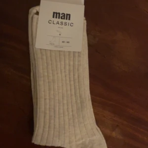 Beige klassiska strumpor - Säljer ett par klassiska beige strumpor från Man Classic. De är tillverkade av 78% bomull och 22% polyamid, vilket ger en skön och hållbar känsla. Strumporna är OEKO-TEX certifierade och har en regular passform. Perfekta för en stilren look.